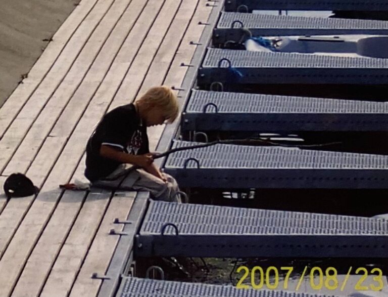 Ein kleiner Junge fischt in einem norwegischen Hafen.